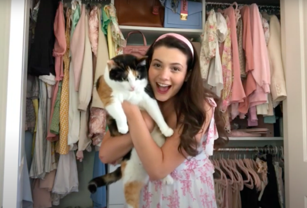 Kaitlyn Riccio youtuber holding her cat in front of her closet which is full of cool pink clothes