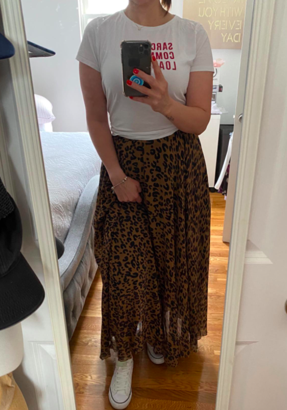 reviewer wearing leopard print maxi skirt in the mirror with a white t-shirt and white sneakers