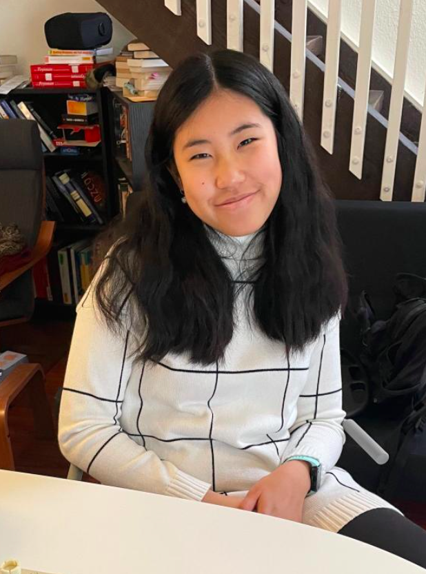 chicwish reviewer wearing the white and black turtleneck dress while sitting at their desk and smiling