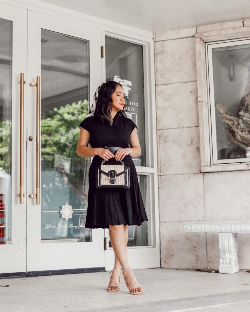 blogger wearing a black sleeveless pleated knit dress