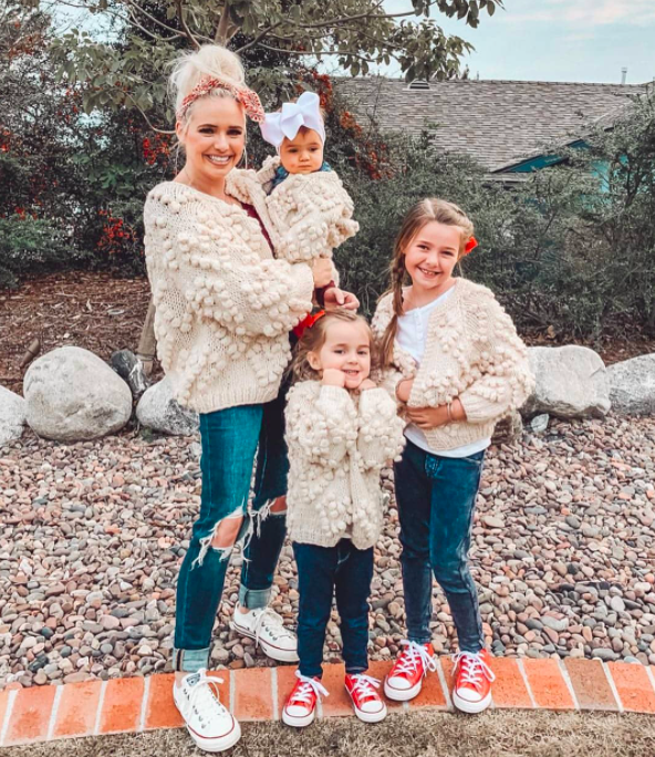 mommy-and-me sweaters in ivory on a family that includes two school-aged girls, a baby, and a mom holding the baby