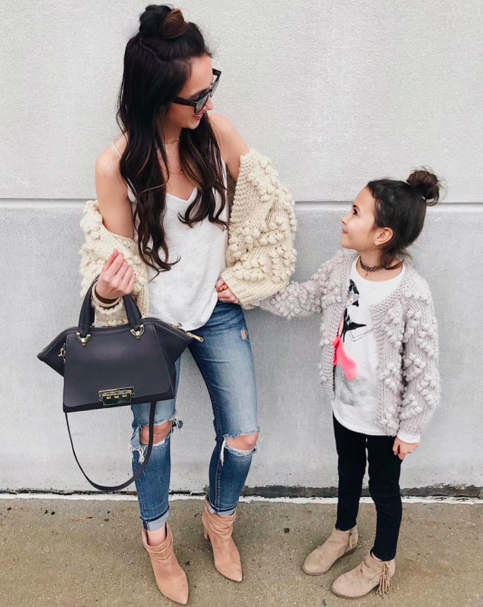 mother and daughter wearing the mommy-and-me sweaters but the mom has on the ivory and the daughter has on the grey lavender one