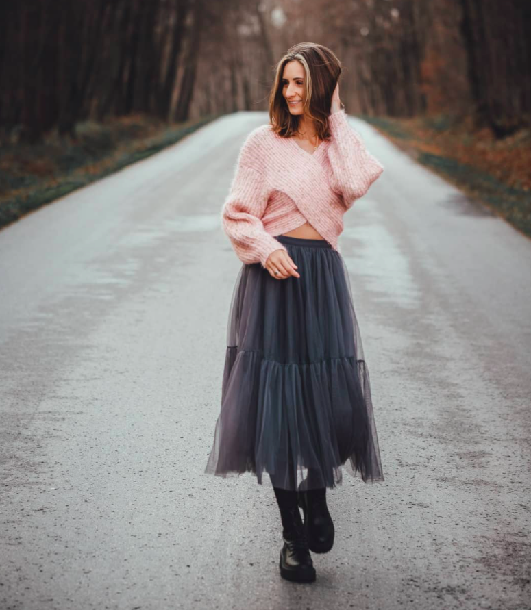 model wearing a pink crisscross sweater and a grey tulle skirt with combat boots