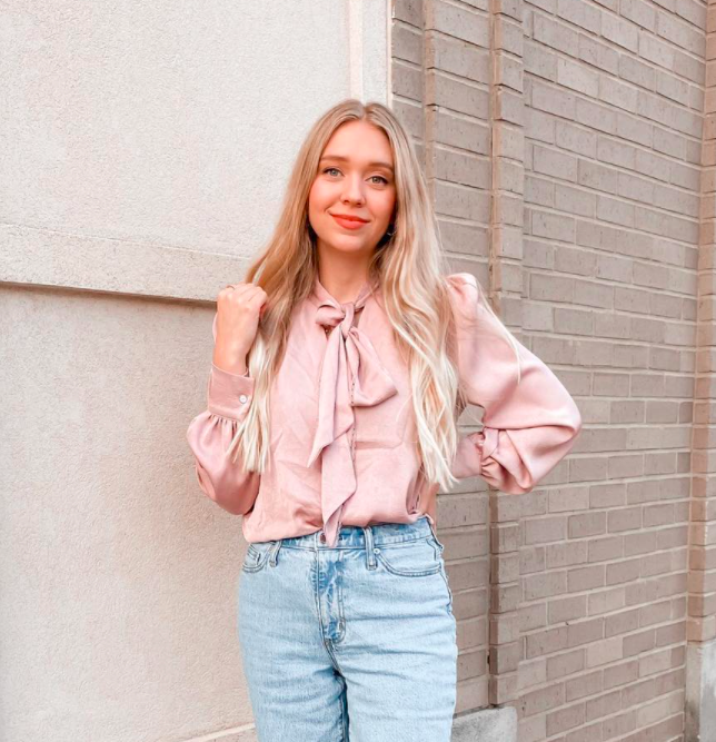 model wearing a long-sleeved light pink bowknot blouse with jeans