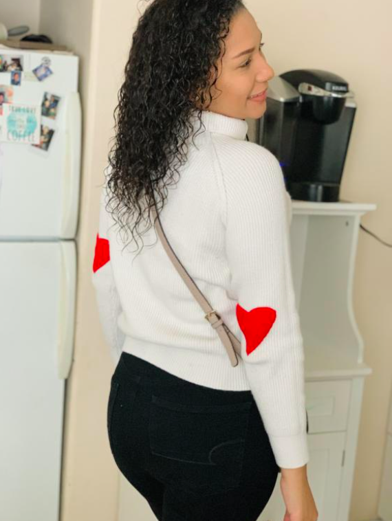 buzzfeed shopper posing in the mirror with a white sweater that has red heart patches on the elbow that's perfect for Valentine's Day