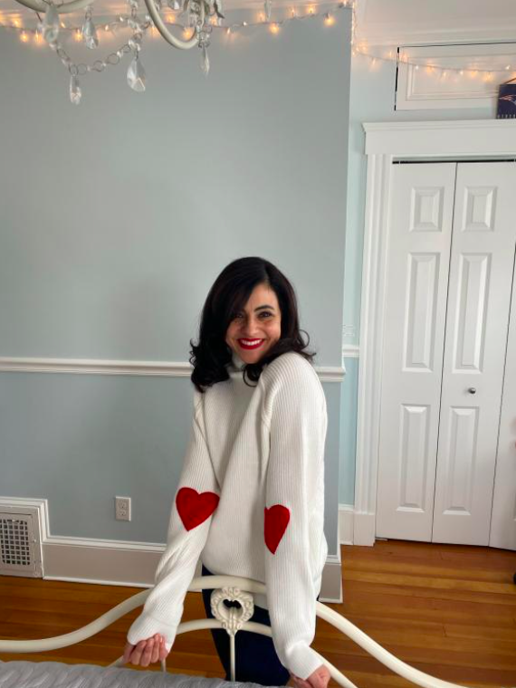 chicwish shopper wearing a white valentine's day sweater with read hearts on the inside of the elbow
