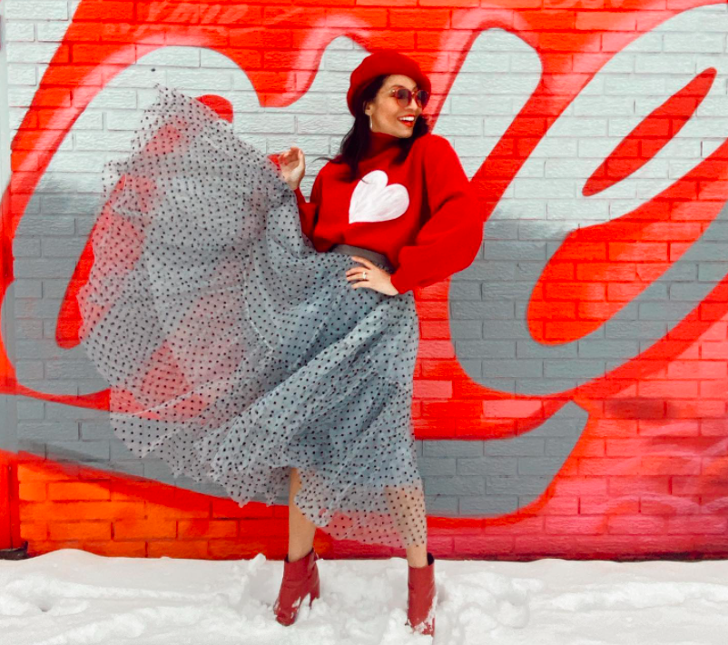 blogger doing Valentine's Day shoot with a red sweater standing in front of a Love street art mural