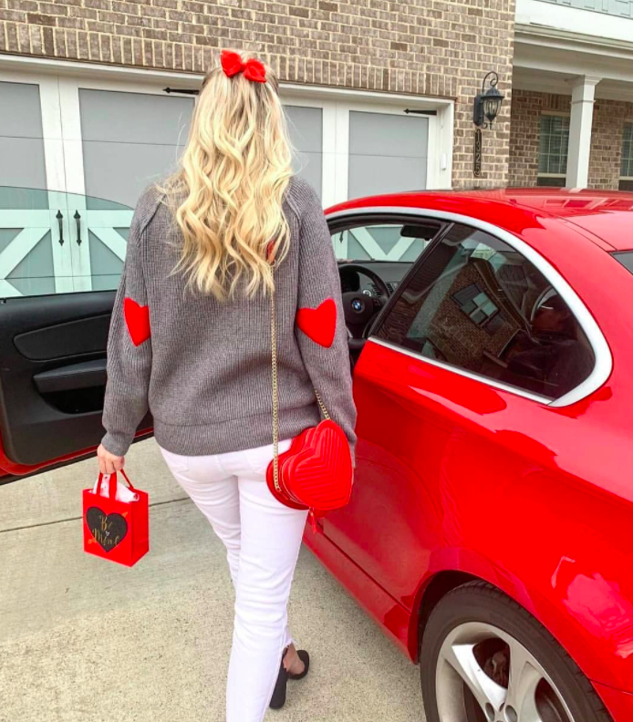 blogger wearing gray sweater with red heart elbow patches