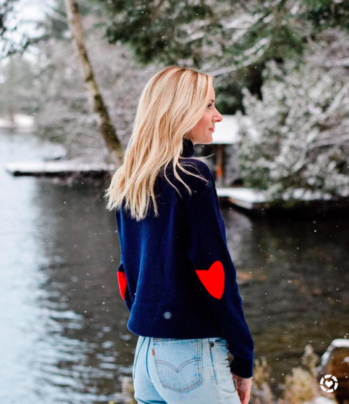 blogger wearing navy sweater with red heart elbow patches